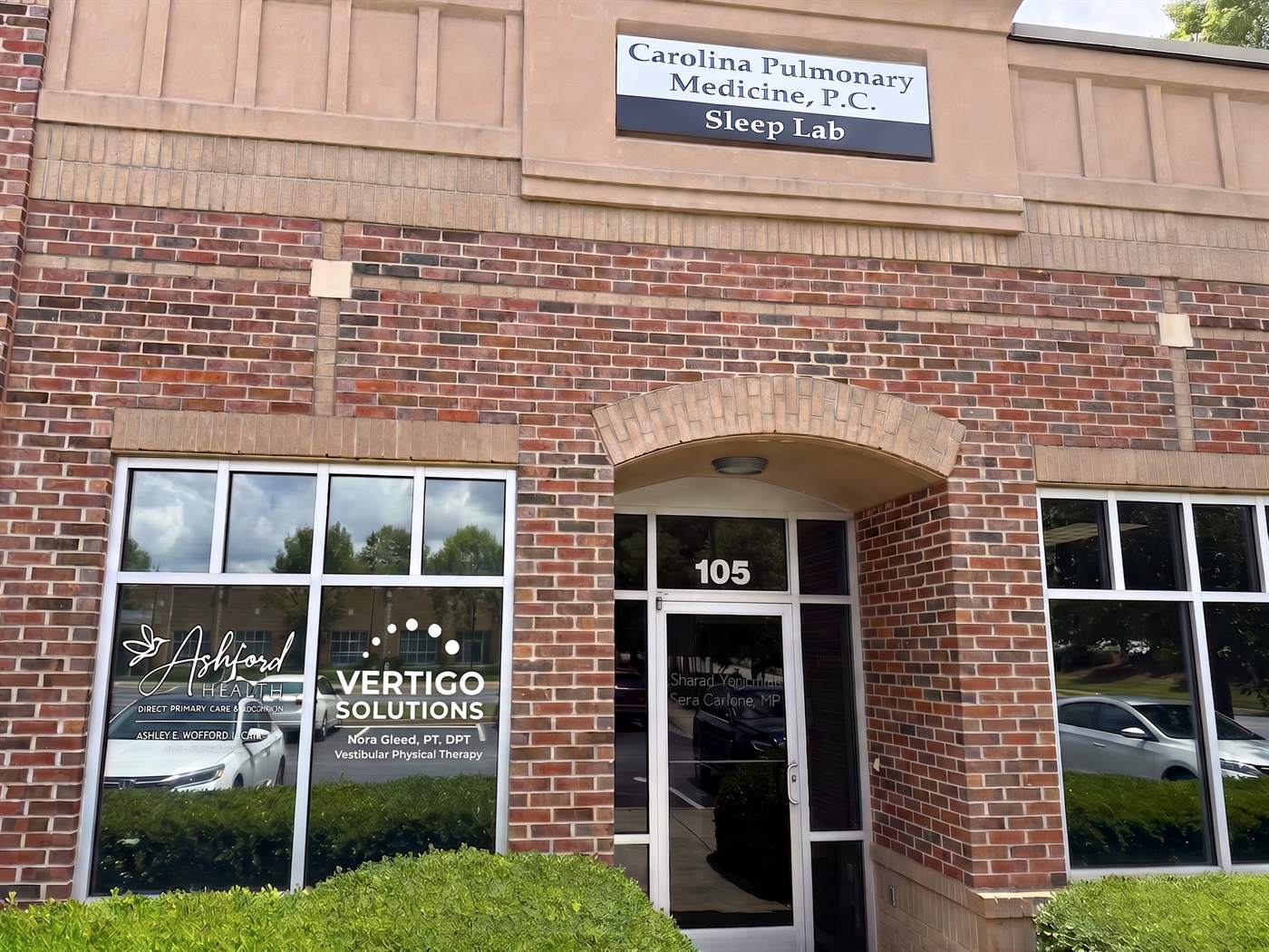 Red-brick storefront at Suite 105 with the Vertigo Solutions logo in the front window, beneath the Carolina Pulmonary Medicine sign